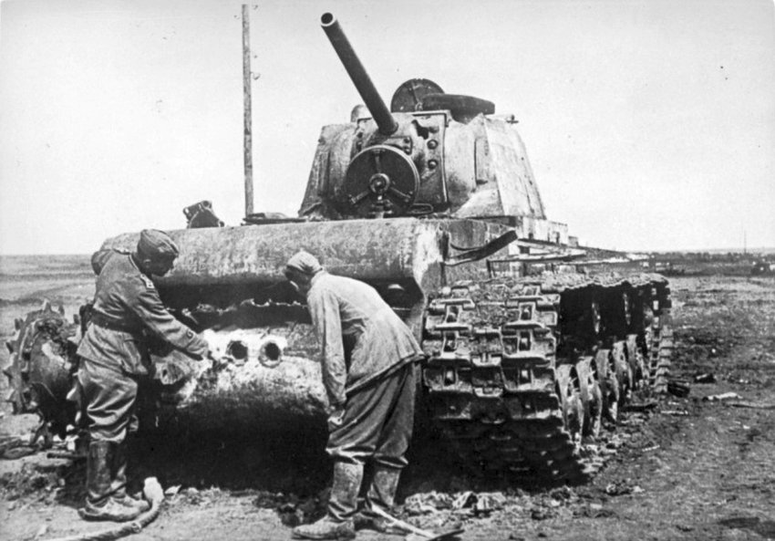 Советский тяжелый танк КВ, подбитый на Керченском полуострове. Май 1942 г. Немецкие солдаты рассматривают сквозные пробоины от 75-мм снарядов в кормовом листе корпуса. / Родина