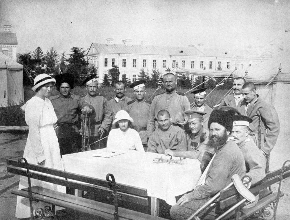 И она же вместе с сестрой Марией (стоит) навещает раненых. 1916 год.